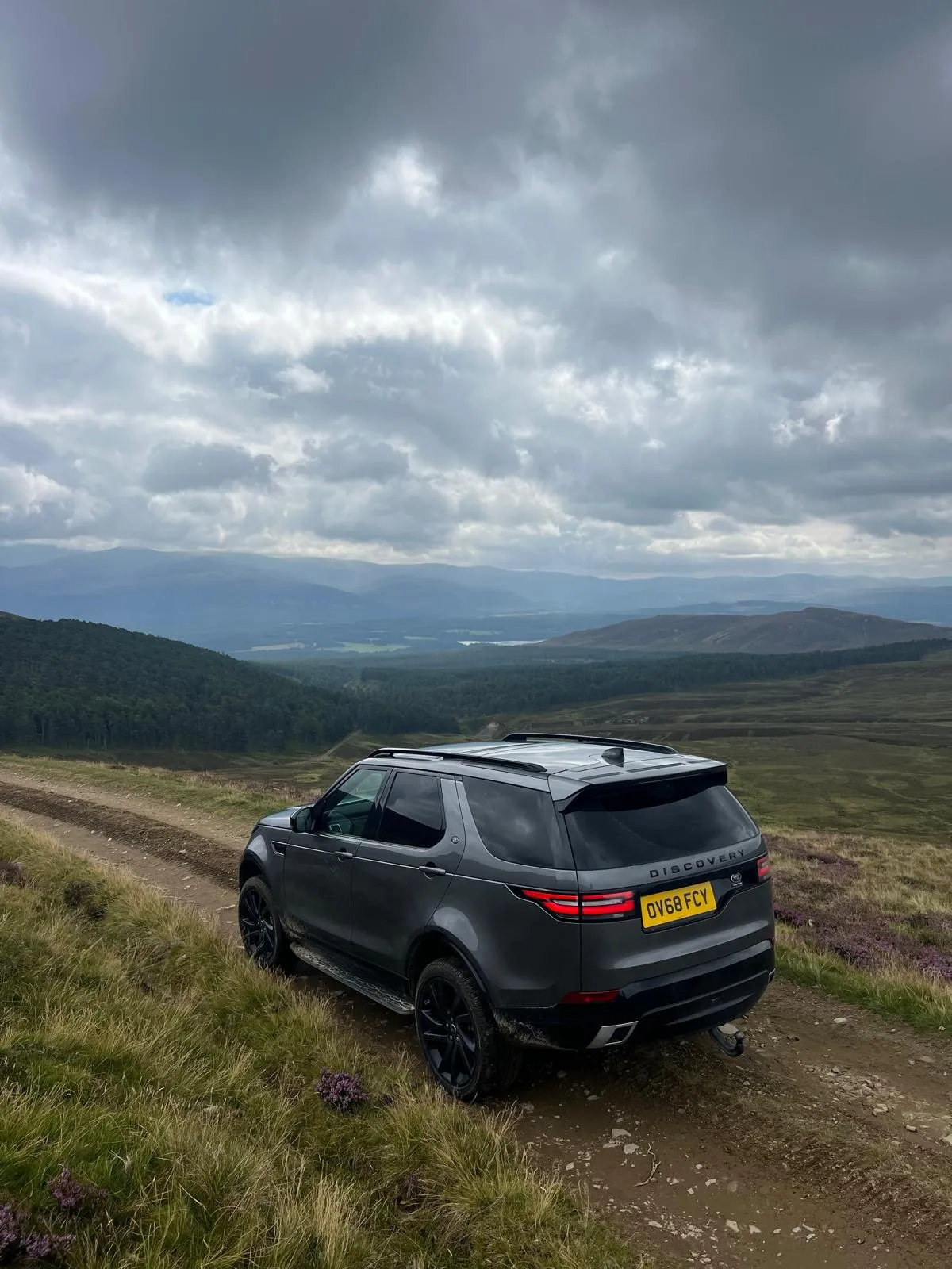 A black car driving down a dirt road.
