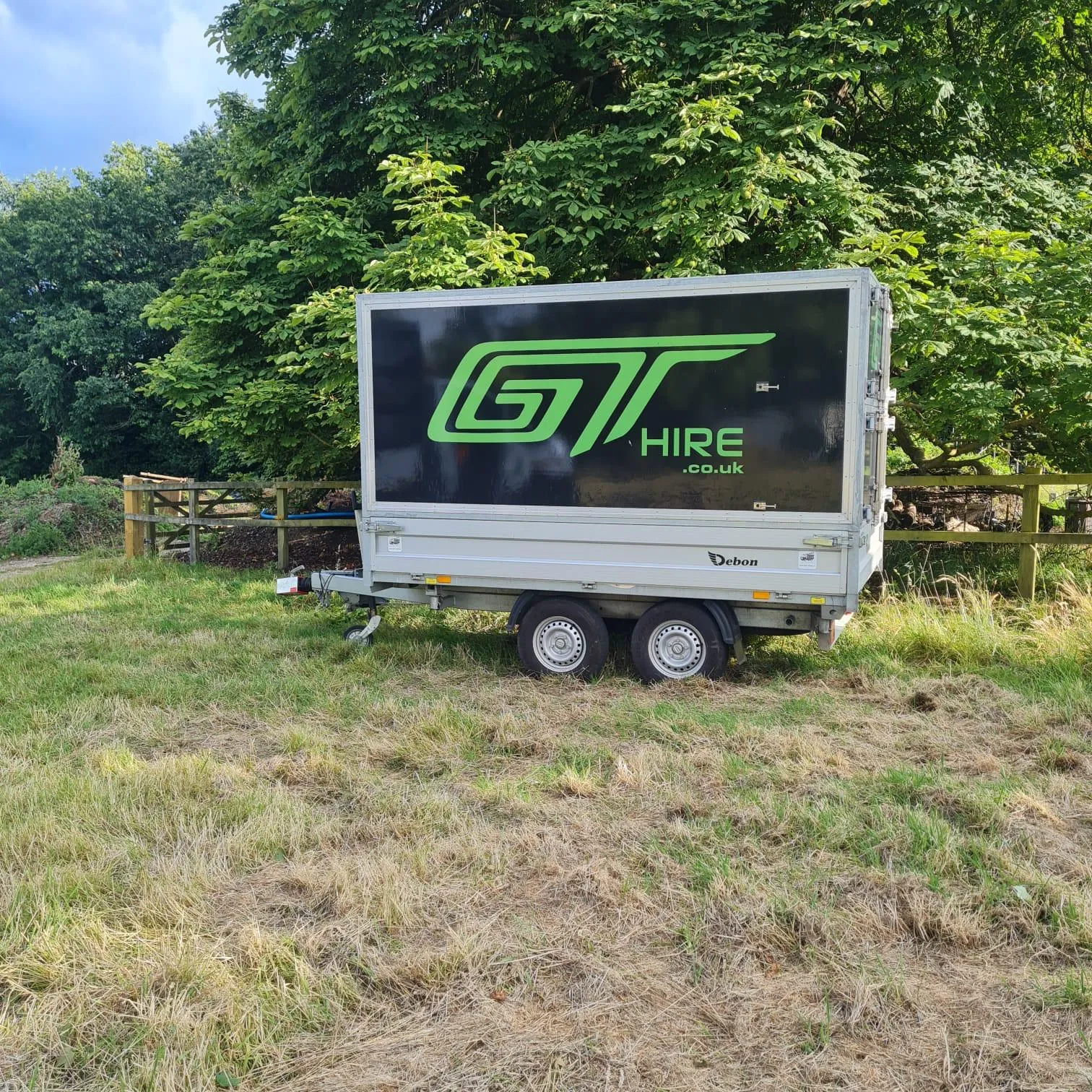 A truck parked in a field with trees in the background.